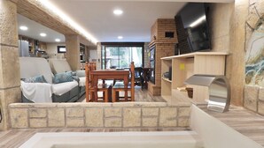 A spa area with a hot tub, wooden furniture, stone walls, and a television.