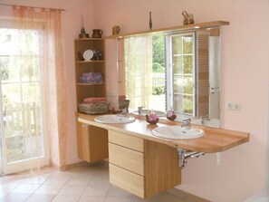 Ein Badezimmer mit zwei Waschbecken, einem großen Spiegel und einer Holzwaschtischgarnitur.