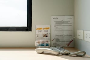 Habitación de hotel con letrero de recepción, un control remoto y un tablón de anuncios.