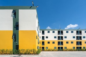 Un edificio de varios pisos con fachada amarilla y blanca, varios balcones y un cielo despejado.