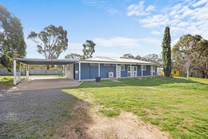 A residential property with a covered outdoor area, a house with a garage, and a well-maintained lawn. - Spacious 5-bedroom 6 acres country house  with AC & dogs run ( pet friendly) (Stawell)