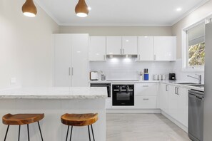 A modern kitchen with white cabinets, a built-in oven, and a stainless steel dishwasher. - Spacious 5-bedroom 6 acres country house  with AC & dogs run ( pet friendly) (Stawell)