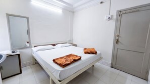 A hotel room with a bed, a bedside table, a mirror, a wardrobe, and a bathroom with a sink. - Hotel Manali-Morbi (Morbi)