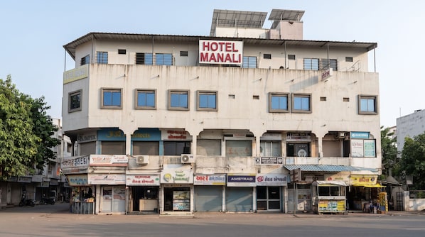 A multi-story building with a sign indicating it is a hotel named 'HOTEL MANALI'.