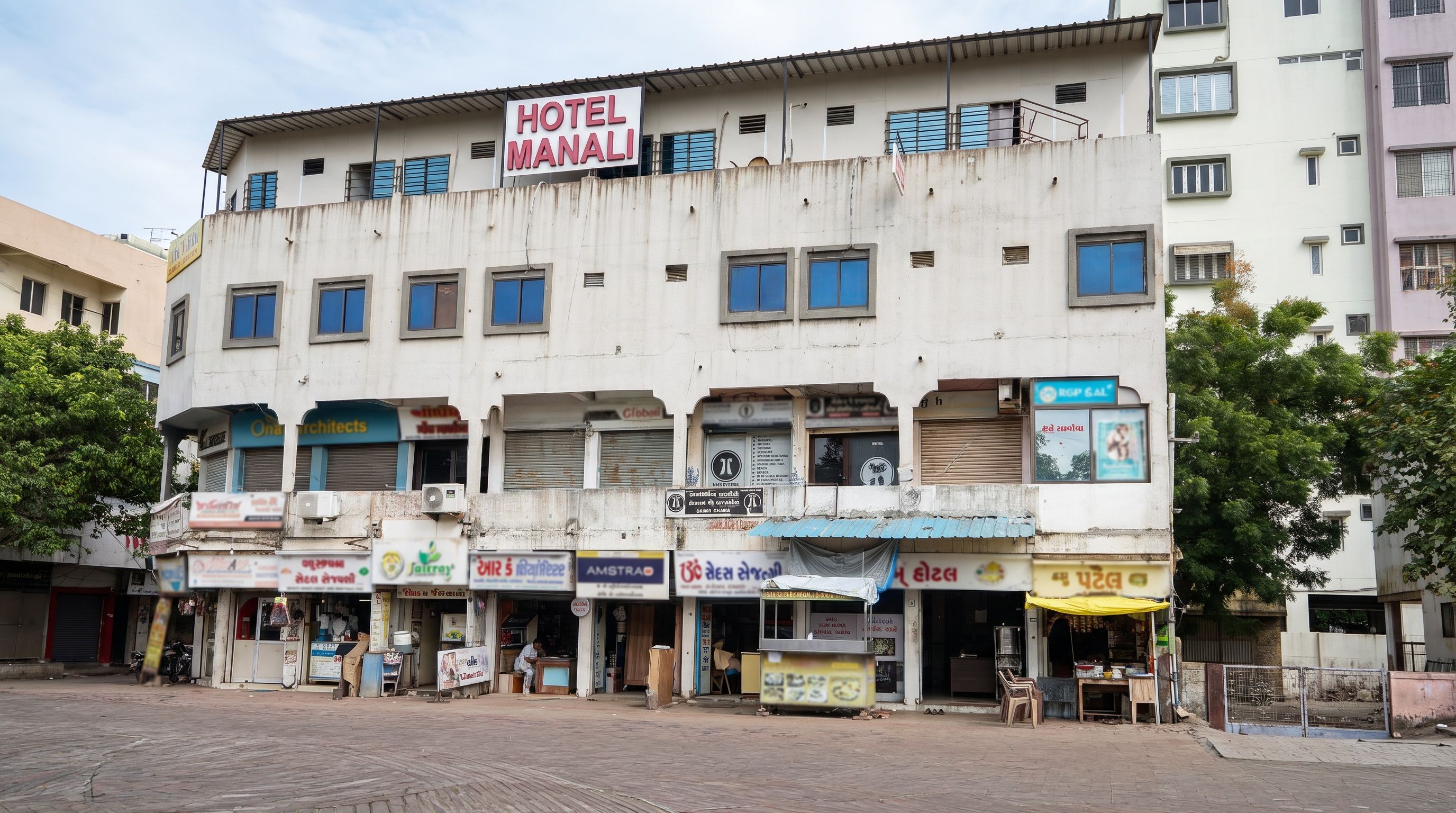 A multi-story building with a sign for 'HOTEL MANALI' on the top.