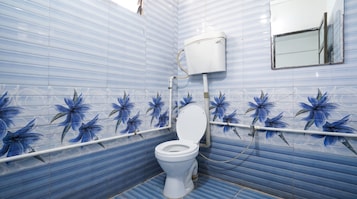 Un baño con inodoro, tanque blanco y espejo en la pared.