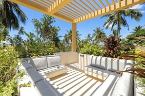 A covered outdoor seating area with a pergola, surrounded by lush tropical vegetation and palm trees. - Brand new 3 BR in Bang Rak(KBR63) (Koh Samui)