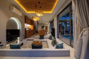 A modern living room with a large flat-screen TV, a sofa set, and a dining area with a table and chairs. - Brand new 3 BR in Bang Rak(KBR63) (Koh Samui)