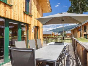 A wooden building with a deck, outdoor seating, and a mountain view. - One-bedroom Cabin (Sankt Georgen am Kreischberg)