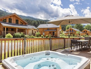 A wooden cabin with a hot tub and outdoor seating area, surrounded by a wooden deck and a fence. - One-bedroom Cabin (Sankt Georgen am Kreischberg)
