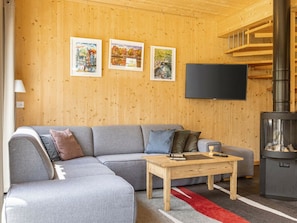 Ein gemütliches Wohnzimmer mit einem grauen Ecksofa, einem Holztisch und einem Kamin.