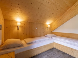 Ein Zimmer mit zwei Betten, Holzwänden und zwei Wandleuchten.
