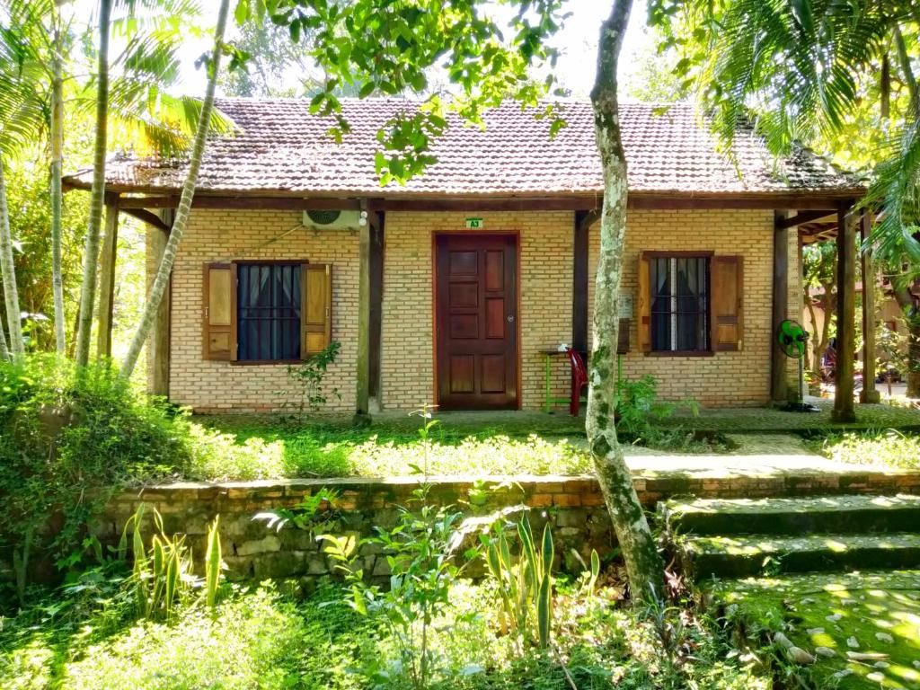 Una pequeña casa de ladrillo con techo de tejas, una puerta de madera y una ventana con persianas.