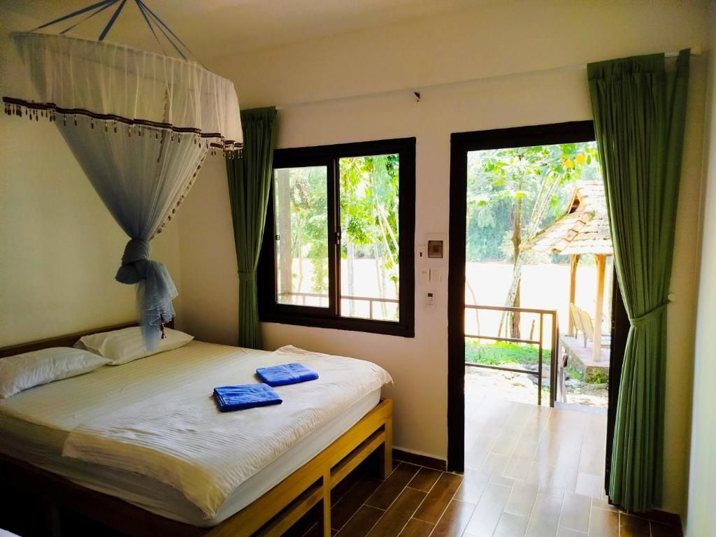 A bedroom with a bed, a window, and a view of the outdoors.