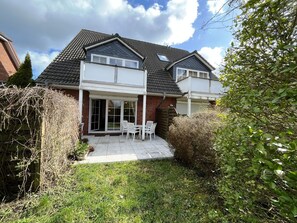 A two-story house with a patio, a covered outdoor seating area, and a brick facade. - Holiday Apartment Seehund – Arrive. Unwind. Enjoy the Sea. (Schönberg (Holstein))