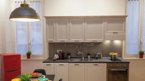Eine kleine Küche mit weißen Schränken, einer Edelstahl-Spüle und einem roten Kühlschrank.
