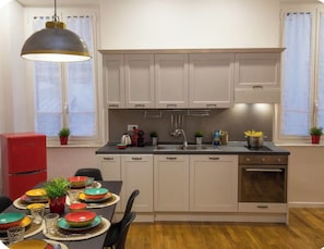 A compact kitchen with white cabinets, a stainless steel sink, and a red refrigerator. - Vrbo Property (roma)