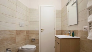 Ein Badezimmer mit Toilette, Bidet, Waschbecken und Schrank.