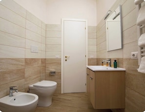 A bathroom with a toilet, bidet, sink, and cabinet. - Vrbo Property (roma)