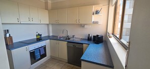 A compact kitchen with a built-in oven, dishwasher, and a window with a view. - Sunrise Spectacular (Soldiers Point)
