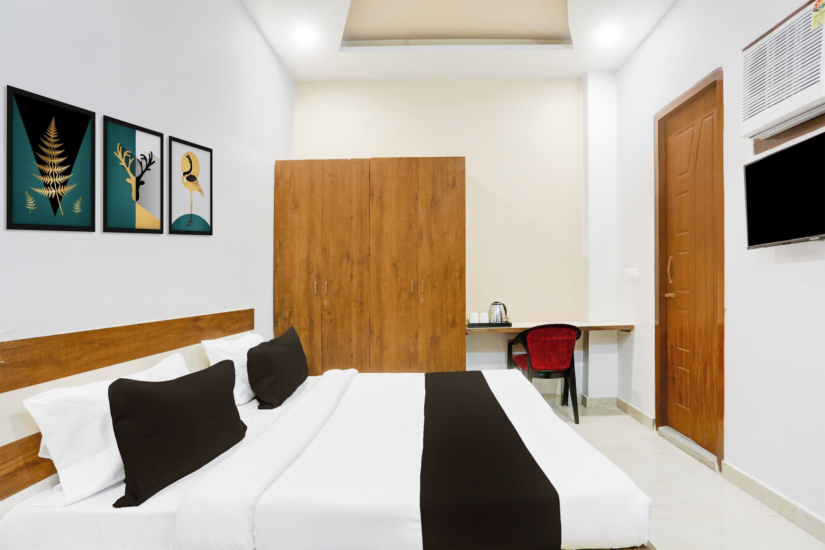 Habitación de hotel con cama, escritorio, silla, armario y obras de arte en la pared.