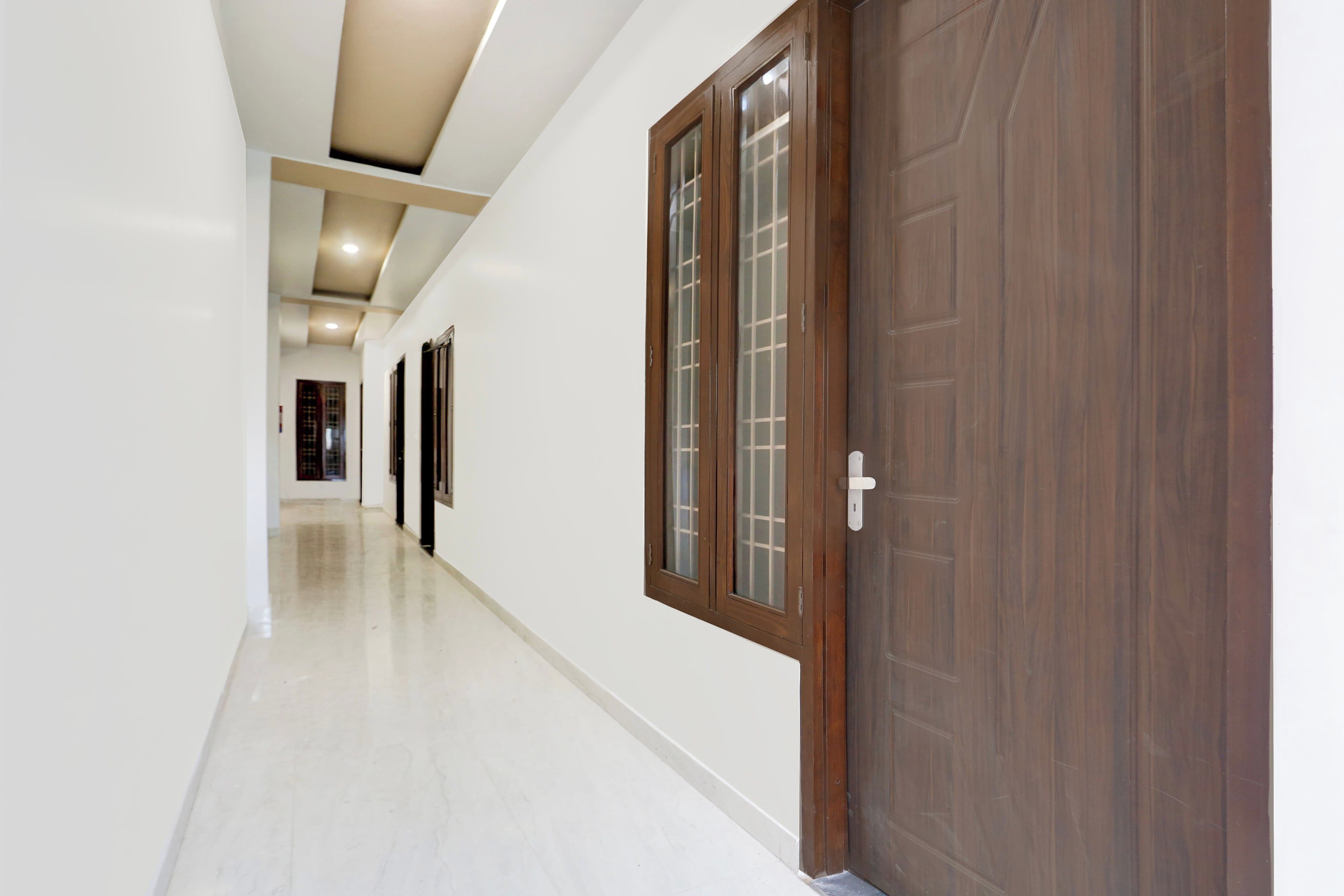 Un pasillo con una puerta de madera y una ventana a la derecha, que conduce a una habitación.