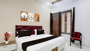 A hotel room with a bed, a chair, and artwork on the wall. - OYO Hotel O Bareilly Near Bus Stand (Bareilly)