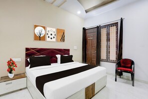 A hotel room with a bed, a chair, and artwork on the wall. - OYO Hotel O Bareilly Near Bus Stand (Bareilly)