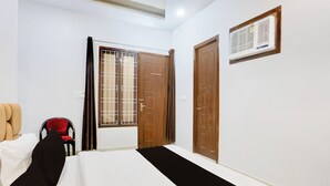 A hotel room with a bed, a chair, a window with curtains, and a door. - OYO Hotel O Bareilly Near Bus Stand (Bareilly)