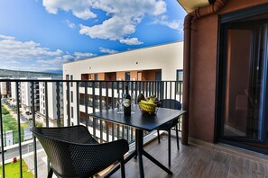 Un balcon avec une table, des chaises et une bouteille de vin.