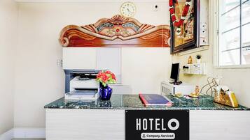 A hotel reception desk with a clock, a printer, and a vase with flowers.