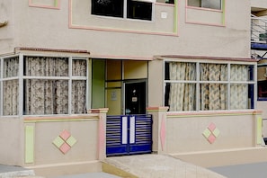 A two-story building with a flat facade, a central entrance, and a blue gate.