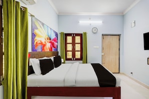A hotel room with a bed, a painting, a clock, and a door. - Super Hotel O Chittoor Railway Station (Chittoor)