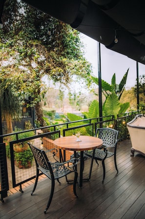 An outdoor patio with a round table and two chairs, surrounded by a black metal fence.