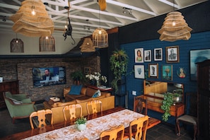 A cozy interior with a brick wall, a television, and various framed artworks. - The Bohemian Guesthouse (Tzaneen)