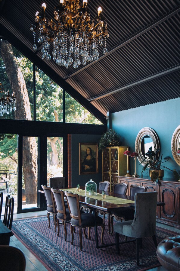 A dining area with a chandelier, a large table, and chairs.
