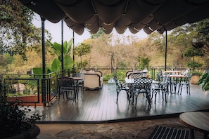 An outdoor patio with wooden flooring, metal furniture, and a covered seating area. - The Bohemian Guesthouse (Tzaneen)