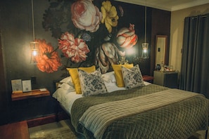 Un dormitorio con una cama grande, una mesita de noche, una lámpara de pared y un espejo.