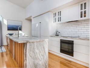 Eine moderne Küche mit weißen Schränken, einer Marmorarbeitsplatte und einem eingebauten Backofen.
