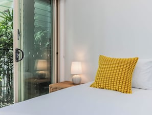 Ein Hotelzimmer mit Bett, Nachttisch mit Lampe und Fenster mit Blick auf Grünflächen.