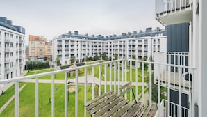 Ein Wohngebäude mit mehreren Balkonen, einem begrünten Innenhof und einem Spielplatz.