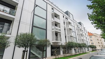 Un edificio moderno con varios balcones, una escalera y una entrada protegida por una puerta.