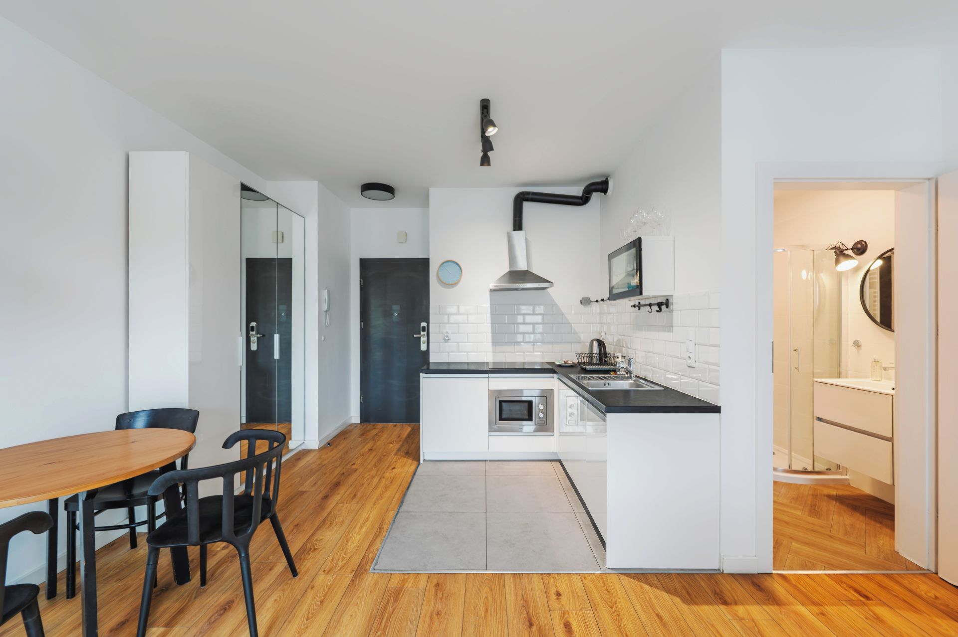 A modern kitchen with white cabinetry, a central island, and a dining area with a wooden table and chairs.