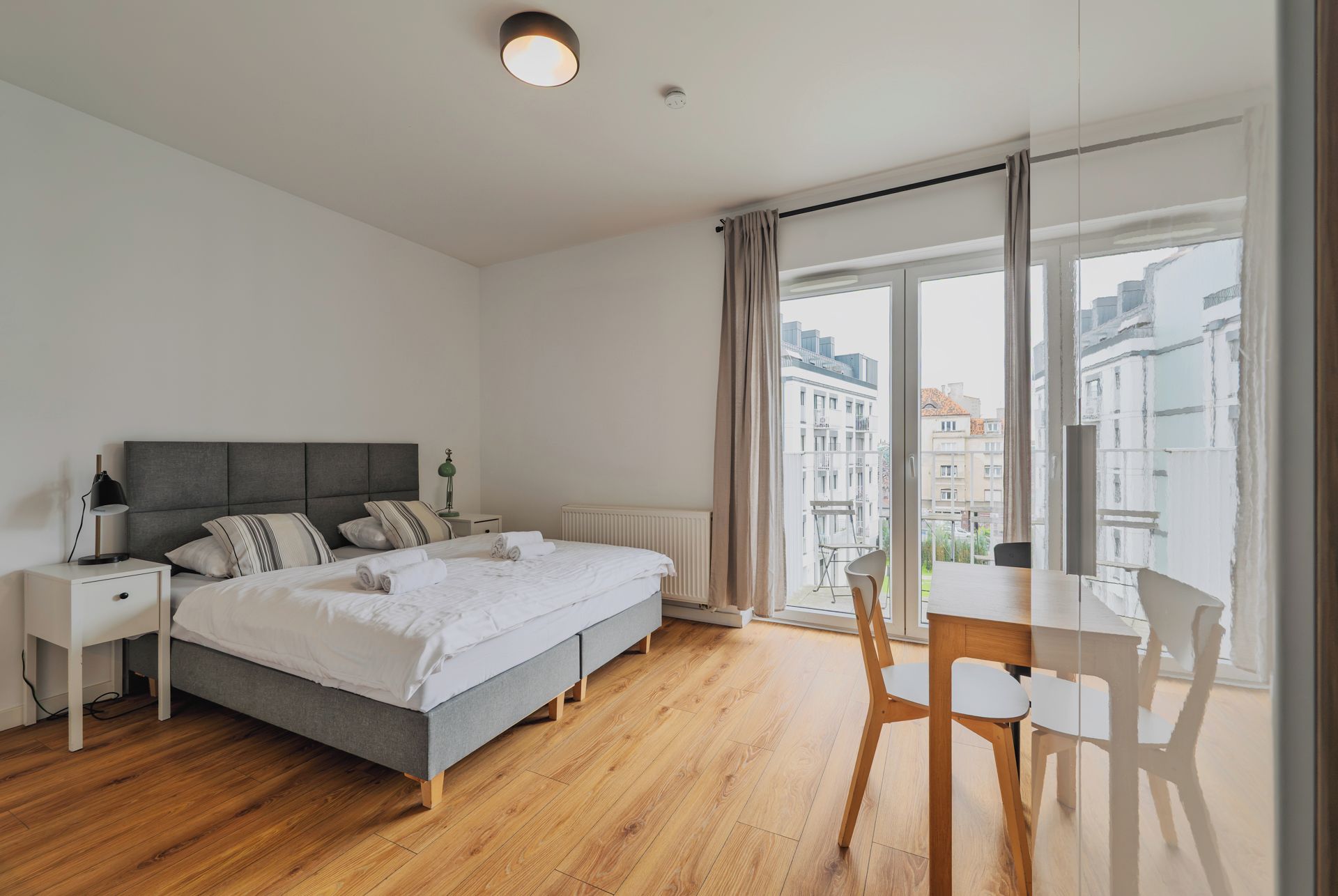 Ein modernes Schlafzimmer mit Bett, Nachttischen, Schreibtisch und Stuhl.