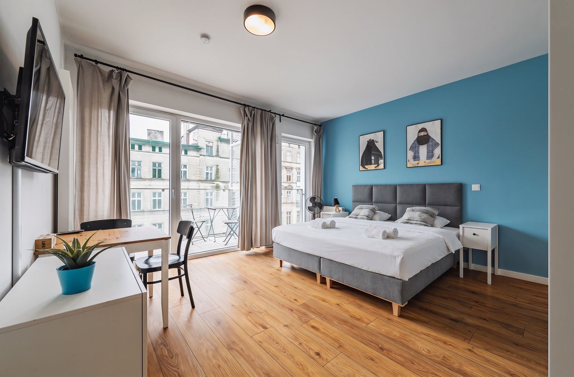 Een moderne slaapkamer met een bed, nachtkastjes, een bureau en een stoel.