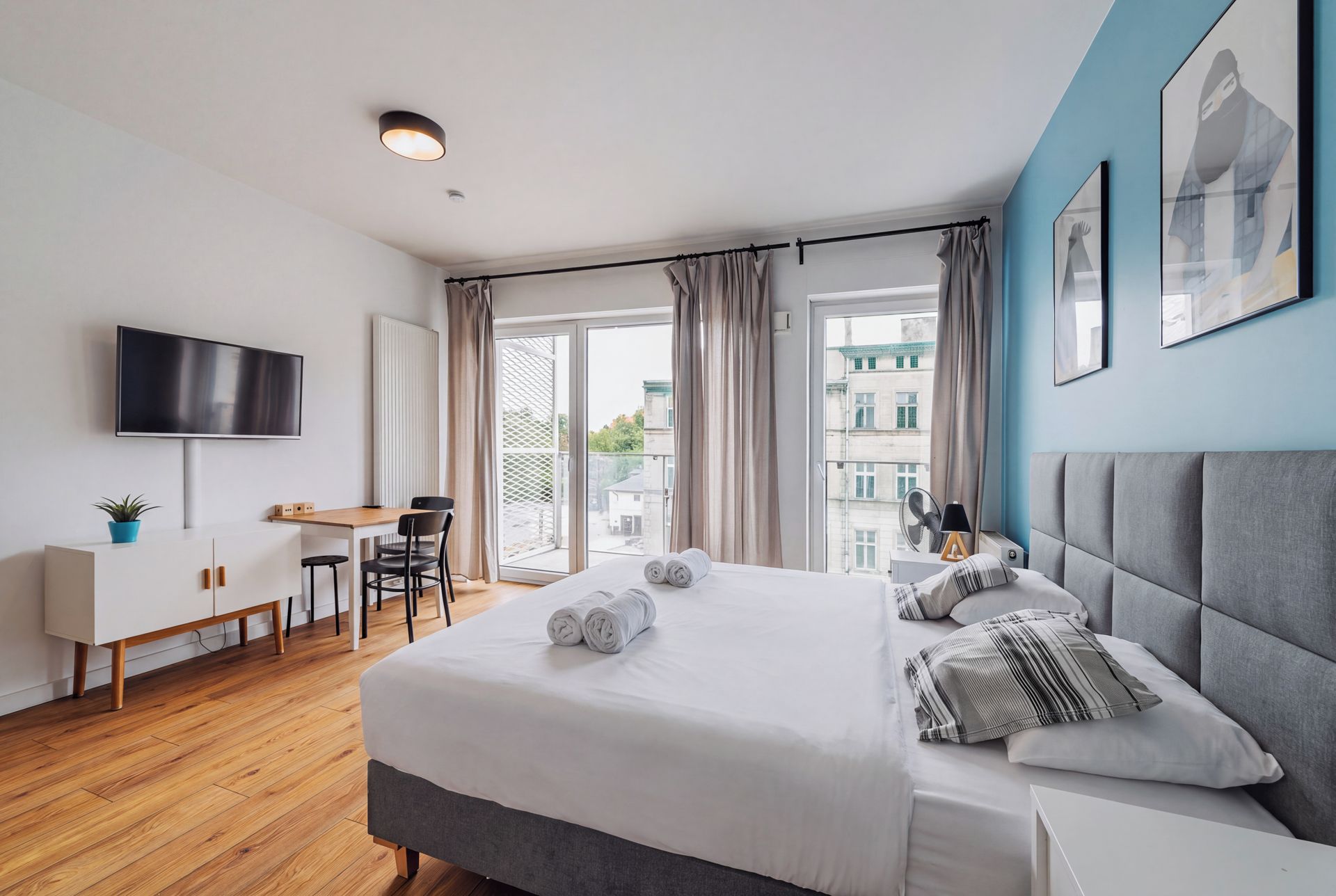 Una camera d'albergo moderna con un letto, una scrivania, una sedia, una TV e vista sugli edifici.