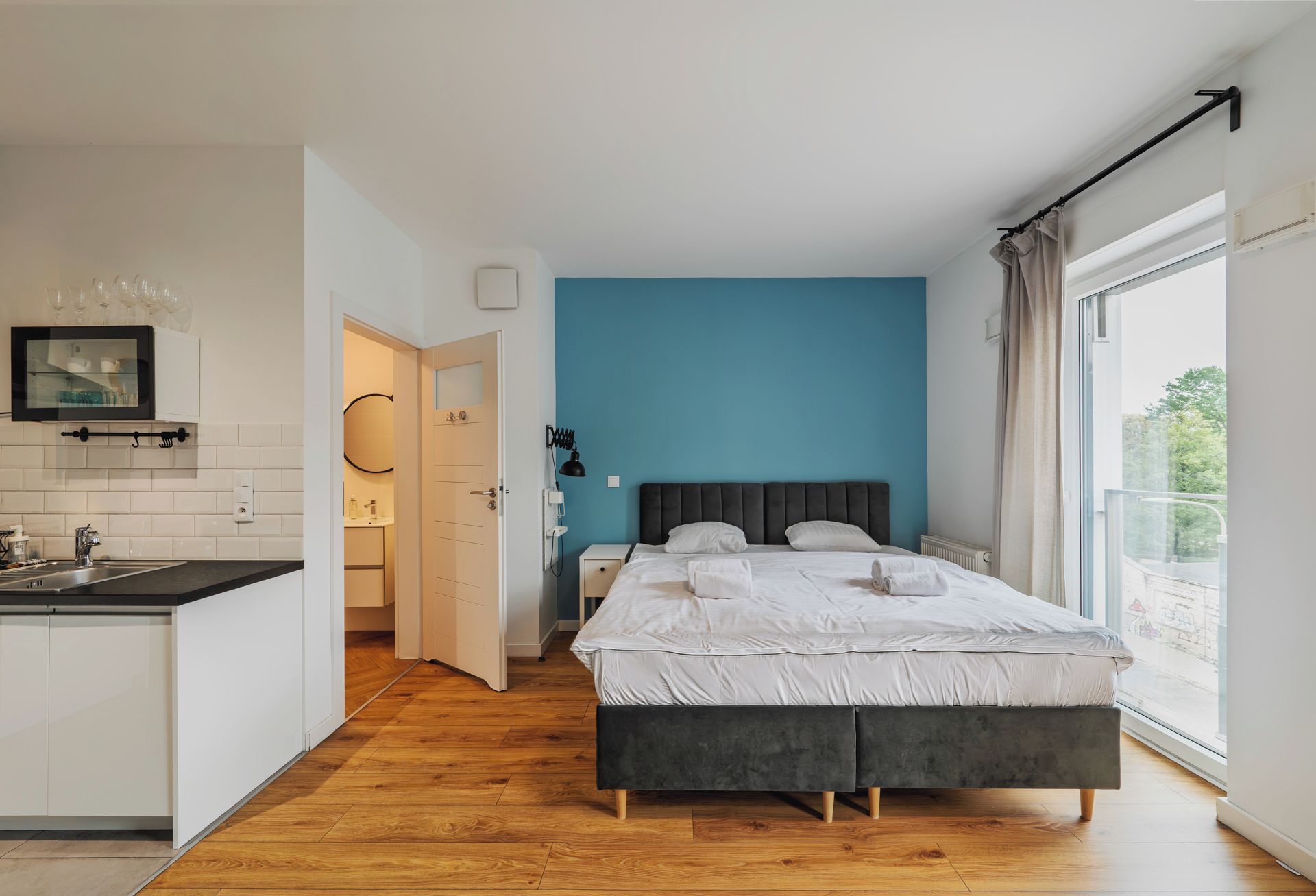 Quarto moderno com cama grande, vista para o exterior e uma kitchenette separada.