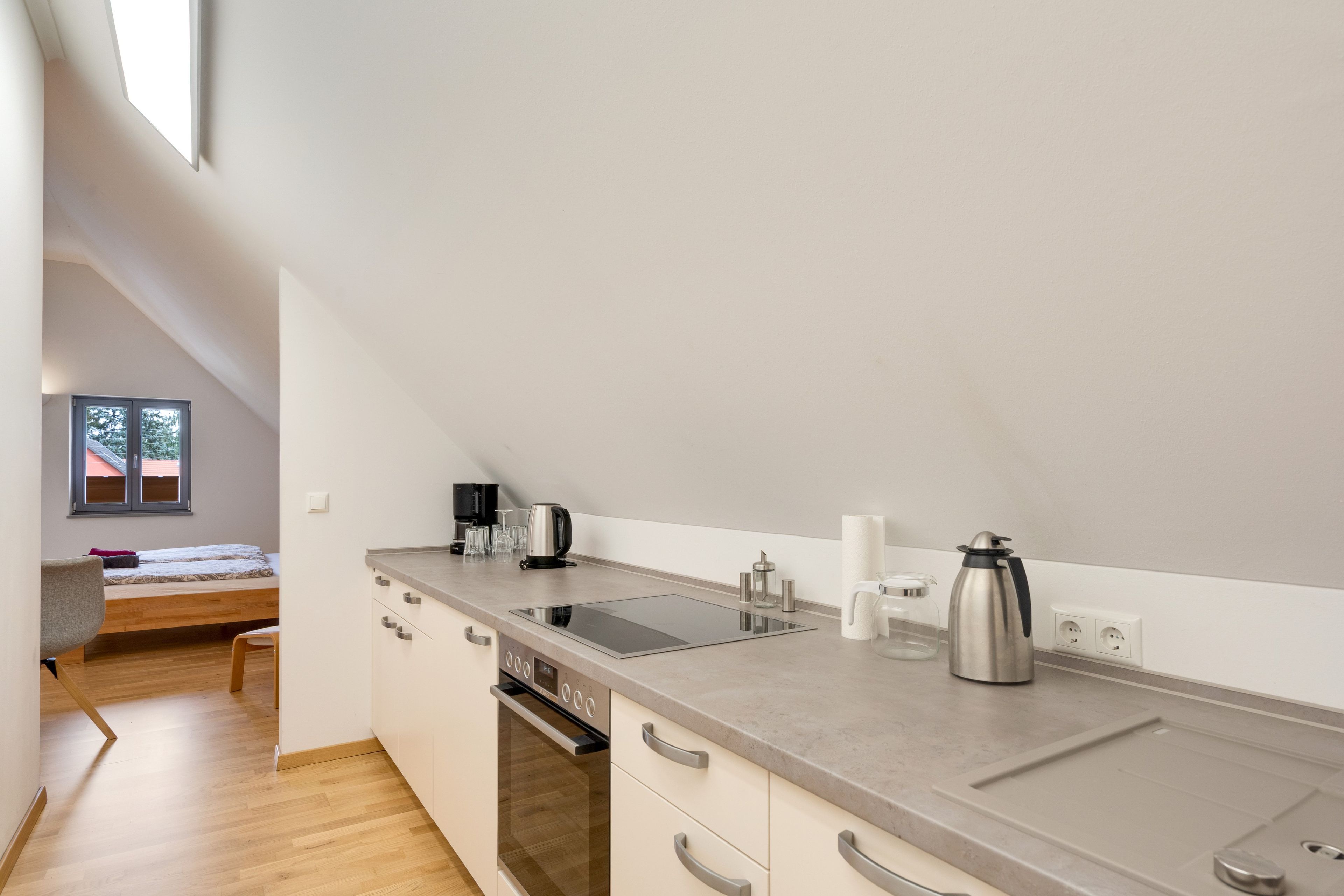 A compact kitchenette with a built-in oven, a coffee maker, and a kettle.