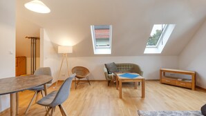 Geräumiges Loft mit Essbereich, Sitzgelegenheiten, einer Couch, einem Fernsehschrank und Dachfenstern.