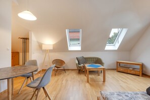 Un loft espacioso con comedor, asientos, un sofá, un mueble para la TV y tragaluces.